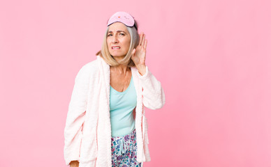 middle age woman looking serious and curious, listening, trying to hear a secret conversation or...