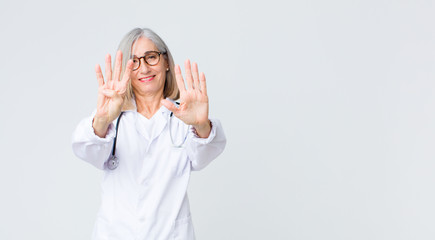 middle age doctor woman smiling and looking friendly, showing number nine or ninth with hand...