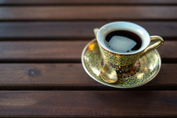 Golden luxury coffee cups Placed on a saucer and a golden spoon on a wooden table