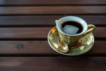 Golden luxury coffee cups Placed on a saucer and a golden spoon on a wooden table