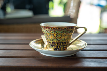 Golden luxury coffee cups Placed on a saucer and a golden spoon on a wooden table