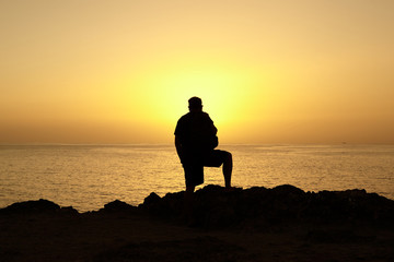 Man silhouette at sunset on the background of the ocean. Amazing sea view