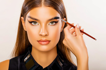 Obraz premium Care beauty eyebrow. Beautiful Young Woman Portrait. Makeup Artist does Face and Eyebrow Makeup. Perfect Bushy Eyebrows. Glossy Peach Lips. Makeup. Beautiful woman with brow brush in hand. 