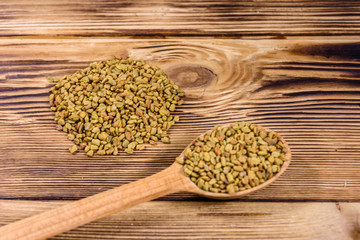 Spoon with fenugreek seeds on wooden table