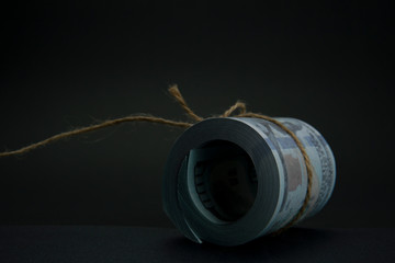 Close up of role money dollar tied with rope on black background.