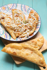 Mexican fried empanadas with cabbage and sauce on turquoise background