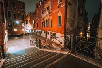 Gothic quarter with old red brick wall houses at night. Empty alleyways and bridge stairs in Venice, Italy
