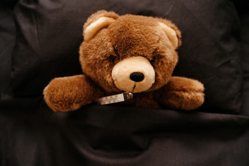 sick patient Teddy bear in bed, fever.