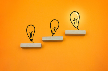 grow up chart with bulb light succeed wooden block on the orange background copy space