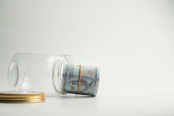 Roll money dollar inside transparent jar on white background. Quotes and finance concept.