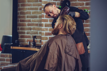 Barber drying male hair in hairdressing salon