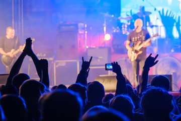 Fototapeta na wymiar Fans in dark neon listening to rock band on stage