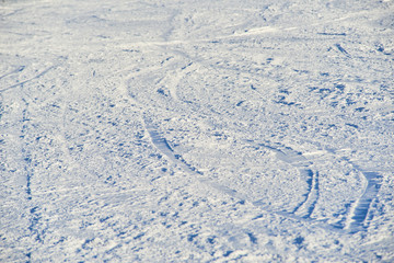 Fototapeta na wymiar Groomed snowy ski slope with trace from skis and snowboards at sun winter day. Low depth of field. Selective focus