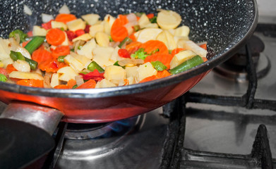 frying vegetables in a red wok pan