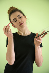 Attractive girl with makeup brushes isolated on green. concept of beauty and health.