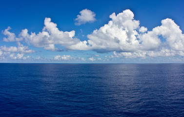 Bright Blue Sky and Ocean With Puffy Clouds