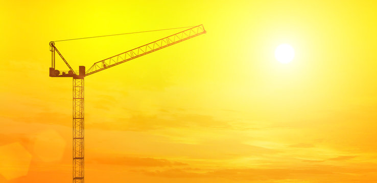 Construction building crane against the sky and sun