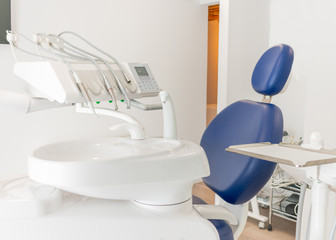 blue dentist armchair with instruments in white cabinet