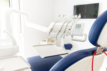 blue dentist armchair with instruments in white cabinet