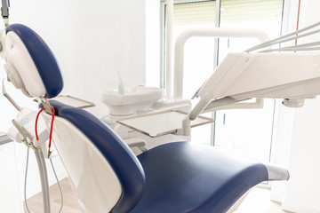 blue dentist armchair with instruments in white cabinet