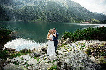 The bride and groom near the lake in the mountains. A couple together against the backdrop of a mountain landscape. Morskie Oko Lake. Tatra mountains in Poland. © ostap_davydiak