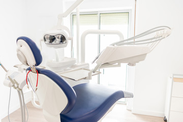 blue dentist armchair with instruments in white cabinet