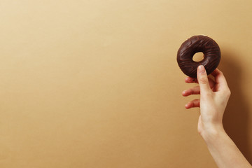 Woman holding delicious donut on color background