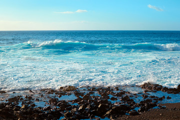 Amazing view of the sea waves on the coast of the island on a summer day. Seaside resort.
