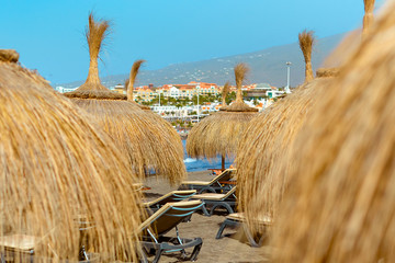 Beach straw umbrellas at the ocean beach. Seaside resort at summer day. Tourism and travel, vacation.