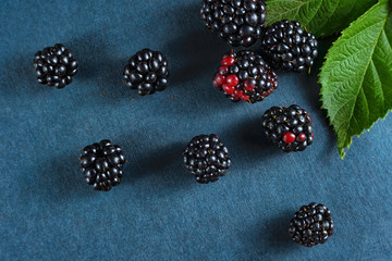 Fresh blackberries, close-ups on a dark background with a green leaf. Top view, flat lay