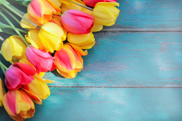 a bouquet of multi-colored tulips lies on a blue-green wooden table. concept of spring mood and romantic mood. the view from the top. space for text