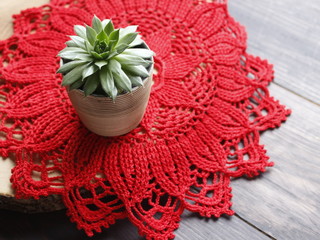Red crocheted doily on a light background. Free space for an inscription. Handwork and needlework.