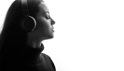 Beautiful woman in headphones listening music with closed eyes. White background. Free space for text.