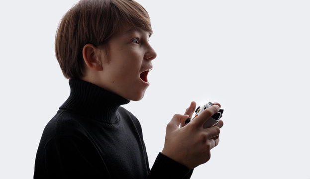 Young boy with joystick in hands playing in video games. White background. Youngster enjoying victory and expresses happiness. Free space for text.