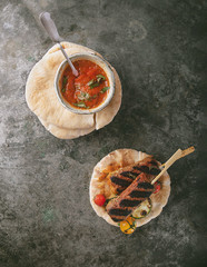Traditional turkish Grilled Lula Kebabs served with vegetables, pita bread and home made tomato sauce over a rustic metal background. Top View.