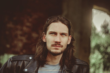 a man in a leather jacket against a brick wall