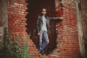 a man in a leather jacket against a brick wall