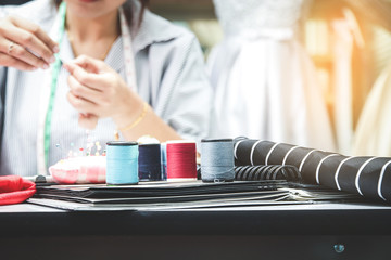 Young female entrepreneurs The owner of a small clothing store is sitting on a fashion design on the desk with sewing equipment. Startup business idea