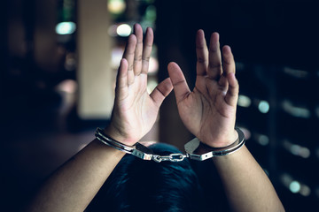 Close up images of The hands of criminals arrested and handcuffed with dark background, to people...