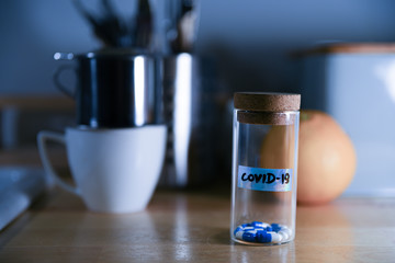 Pills in glass container with name of COVID 19.