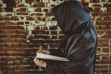 black monk with a book in a cloak