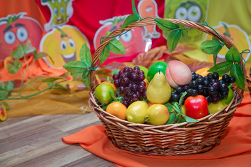 Cucumber, red pepper, carrot, potato, grape in the basket . Basket and artificial fruits on wooden table. Table-still life. The fruits are in the basket.