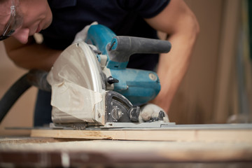 Carpenter in white gloves works on jigsaw