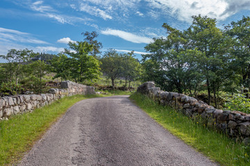 Country road leading over stone wall bridge in Scottish Highlands