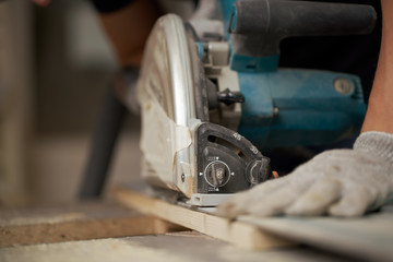 Hands of carpenter sawing wooden boards with jigsaw