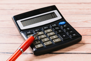 Accounting, financial concept, flat lay, calculator and pen on wooden table