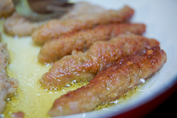 The long cutlet is fried in a red pan. She cooks the cutlet in a white pan . Juicy homemade cutlets beef, pork, chicken .