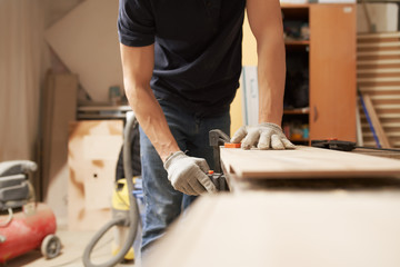 Man carpenter in gloves clamps board in vice at workshop