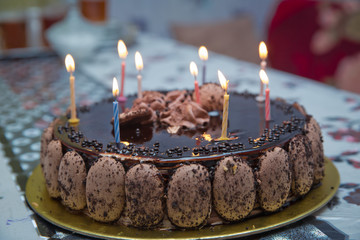 Super chocolate cake with chocolate sauce . Piece of chocolate cake with icing . The cake candles are lit . Delicious vegan chocolate cake. Selective focus.