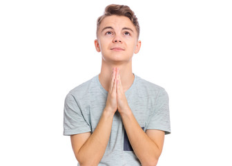 Portrait of teen boy praying, isolated on white background. Cute caucasian teenager with hands folded in prayer hoping for better. Child asking God for good luck, success or forgiveness. Looking up. - 322618255